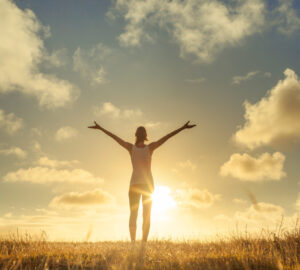 Women with arms in air embracing beautiful scenery and looking at the sky