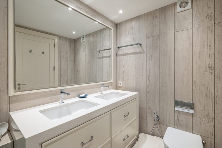 Modern bathroom with large mirror, double sink and faux wood cladding