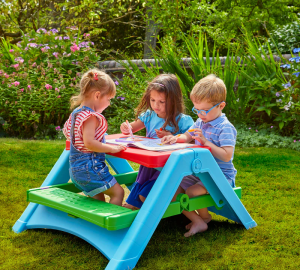 Three children sat at plastic kids table