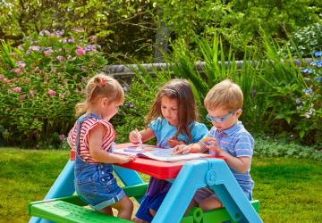 Three children sat at plastic kids table