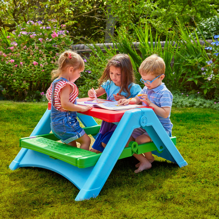 Three children sat at plastic kids table