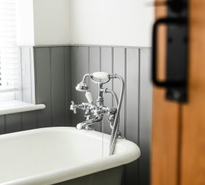 Roll top bath in bathroom with grey wall panelling