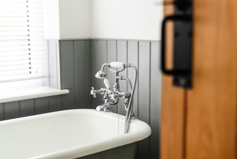 Roll top bath in bathroom with grey wall panelling