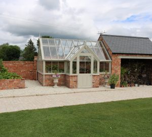 Garage with attached brick and wooden greenhouse