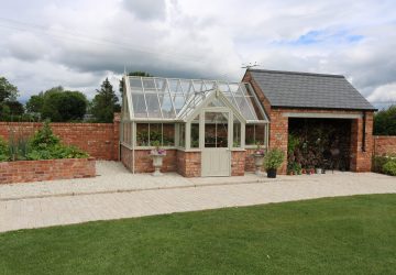 Garage with attached brick and wooden greenhouse