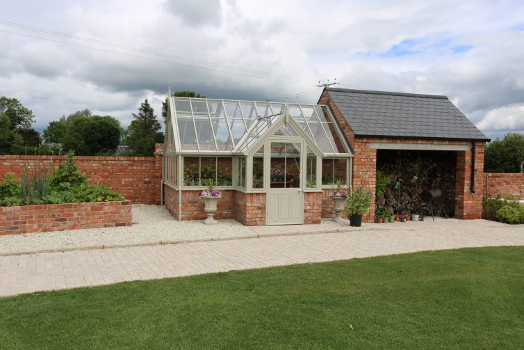 Garage with attached brick and wooden greenhouse