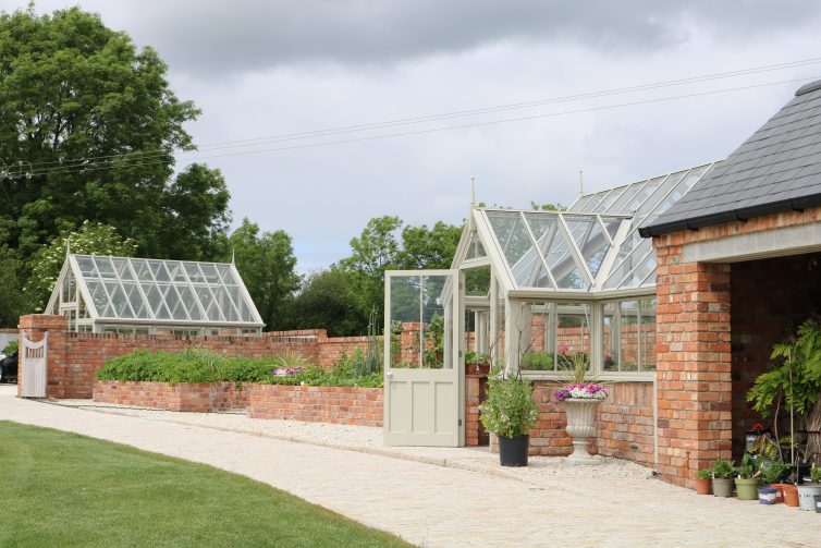 Garage with attached brick and wooden greenhouse