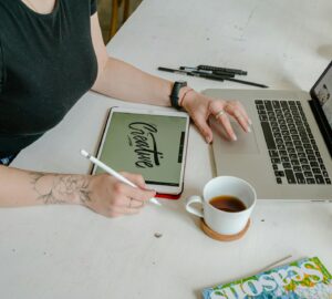 person sitting at desk with laptop and table. Creative writen on tablet