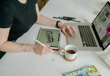 person sitting at desk with laptop and table. Creative writen on tablet