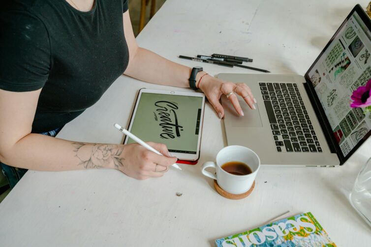 person sitting at desk with laptop and table. Creative writen on tablet