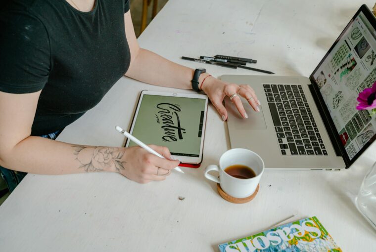 person sitting at desk with laptop and table. Creative writen on tablet